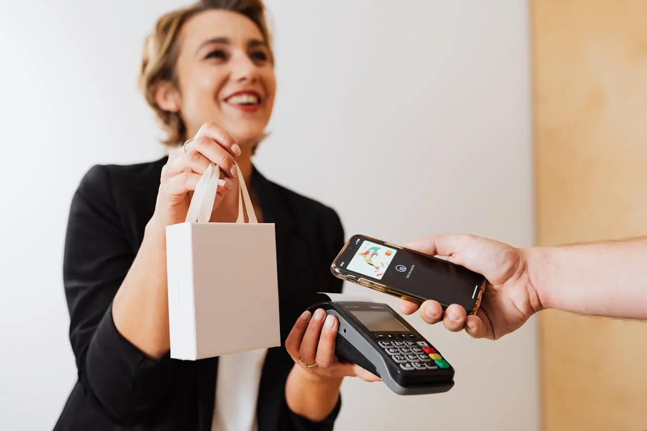 Smiling cashier handles a purchase with a contactless mobile payment in a modern shop.