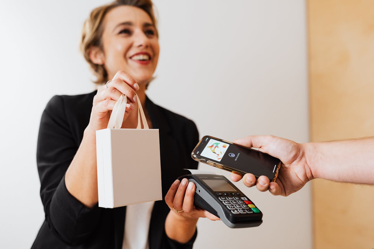 digital Smiling cashier handles a purchase with a contactless mobile payment in a modern shop.
