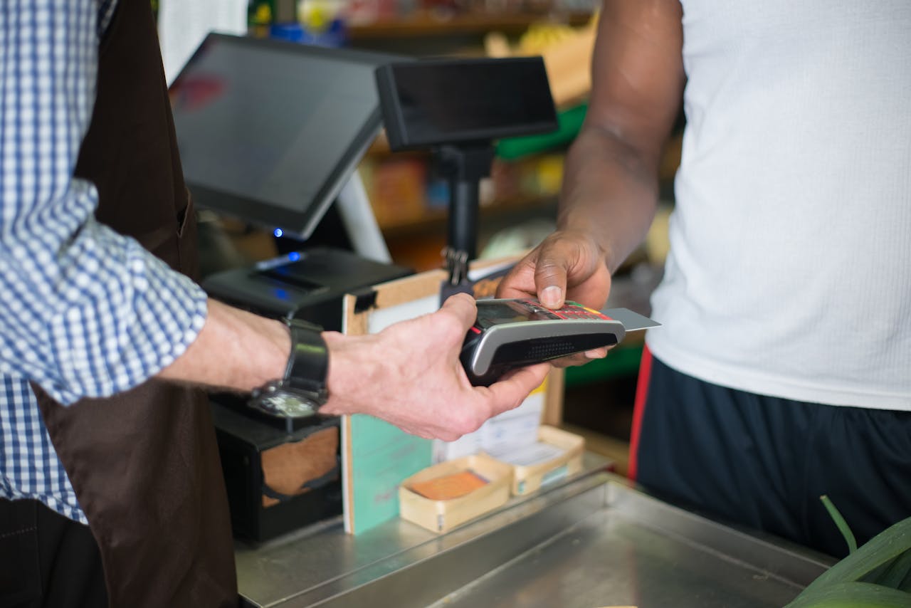Services-01 A customer making a payment with a credit card at a store checkout counter using a card reader.